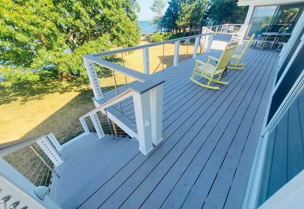 Outdoor deck with seating area overlooking lush greenery and water.