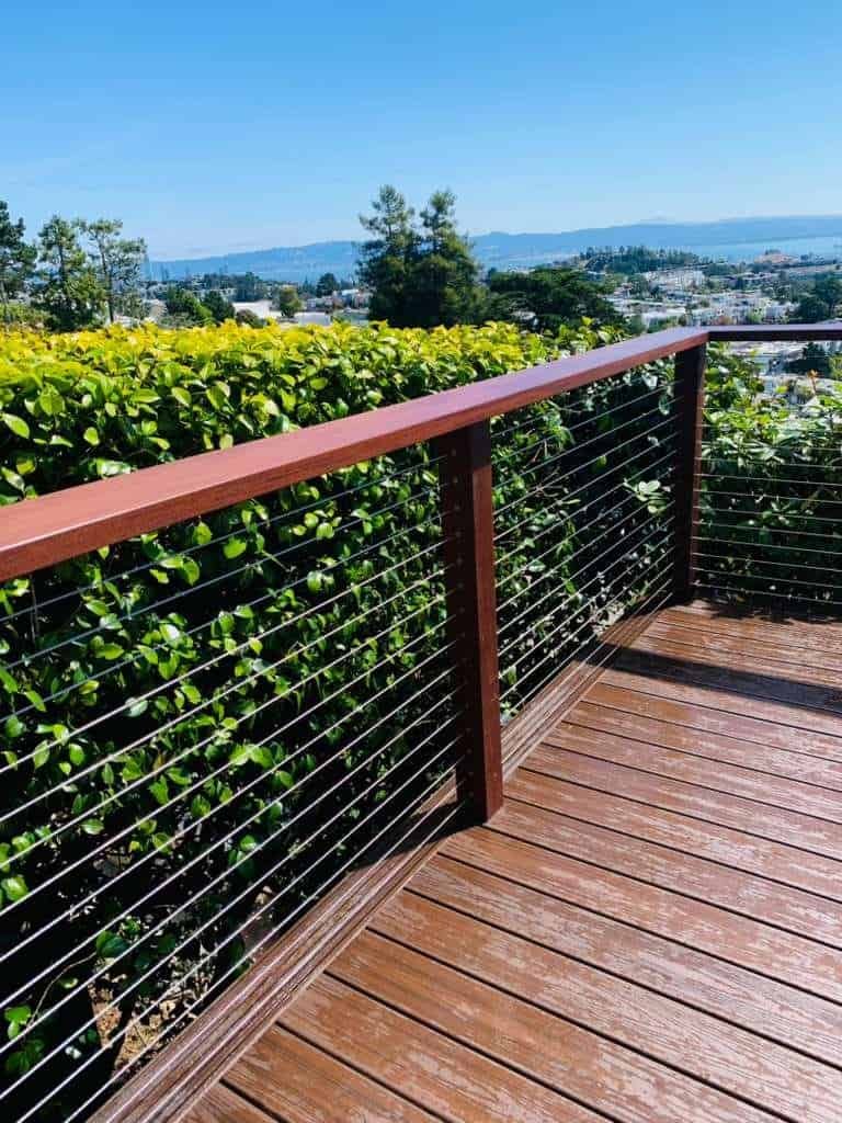 Balcony with wooden deck and modern metal railing overlooking scenic landscape.