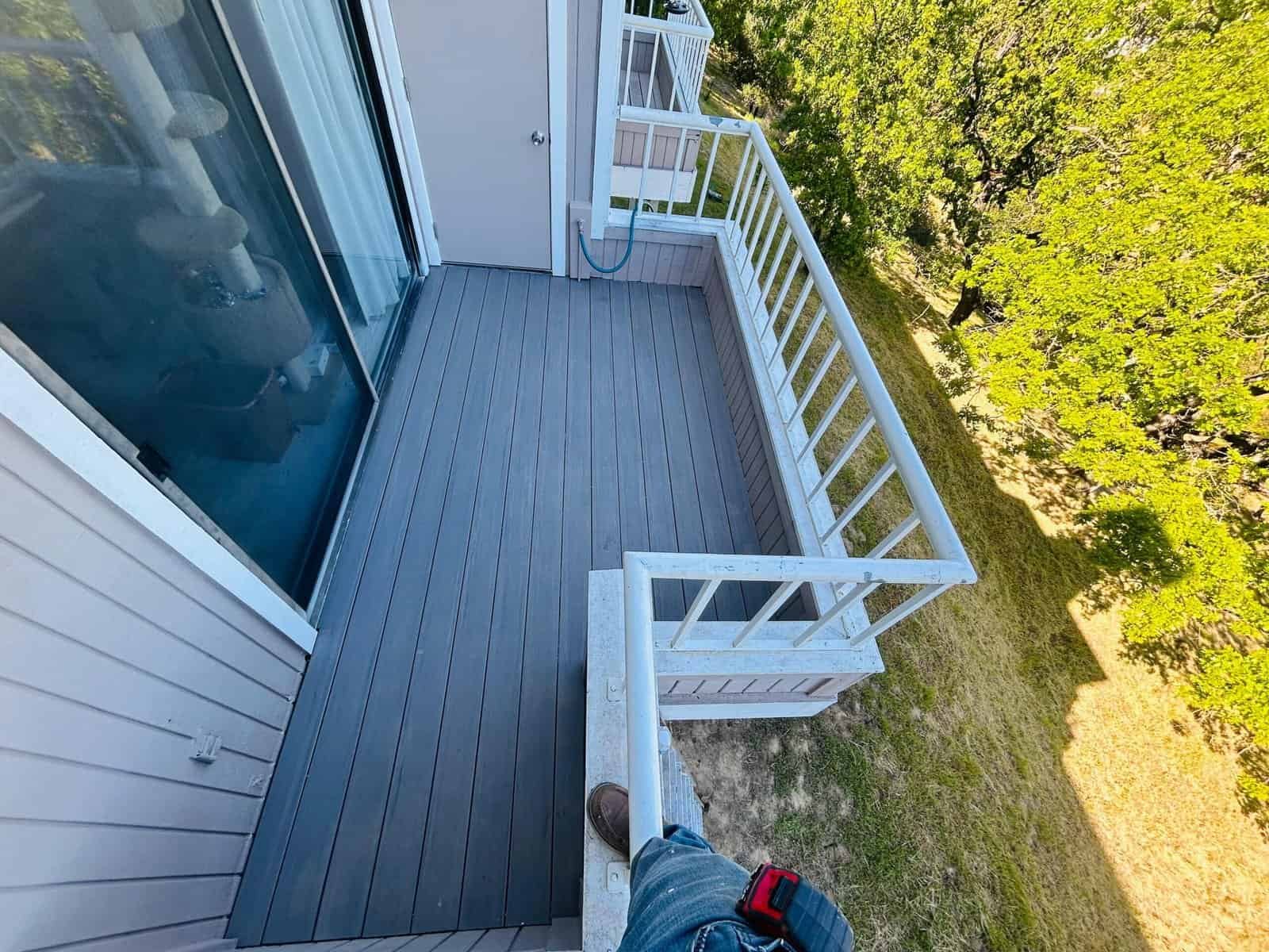Balcony featuring white railing and gray composite decking, perfect for outdoor relaxation and enjoy.